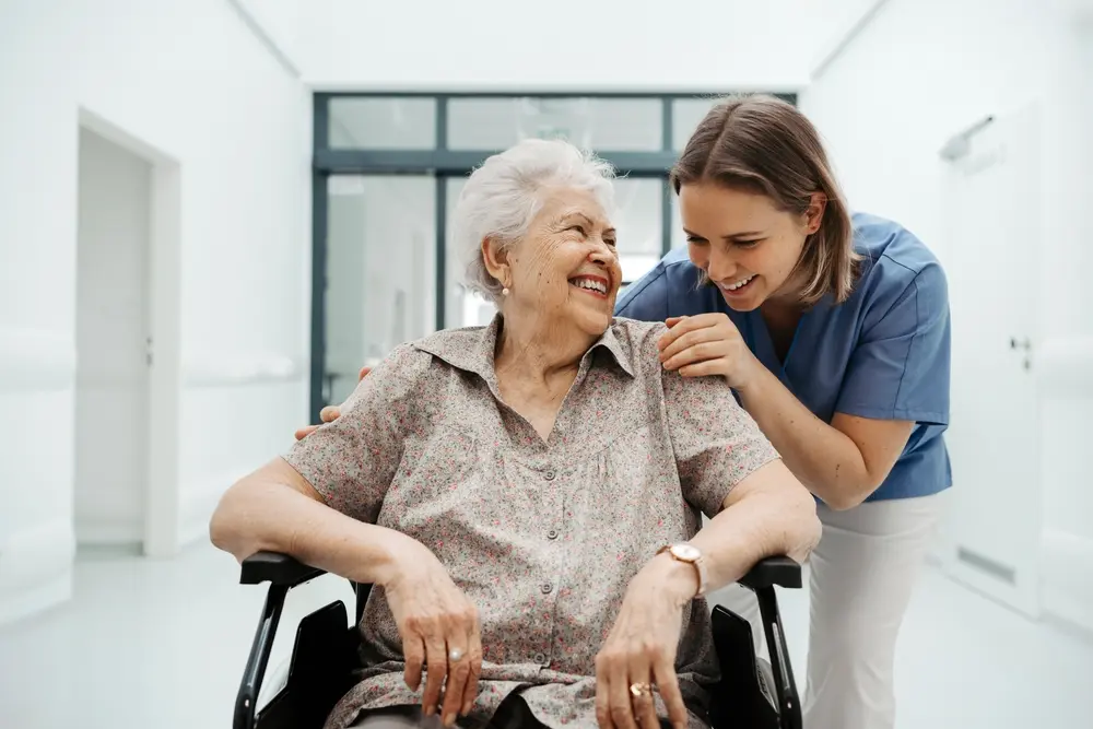 Skilled nursing staff assisting a senior in a wheelchair with 24/7 clinical support at Nirvana House
